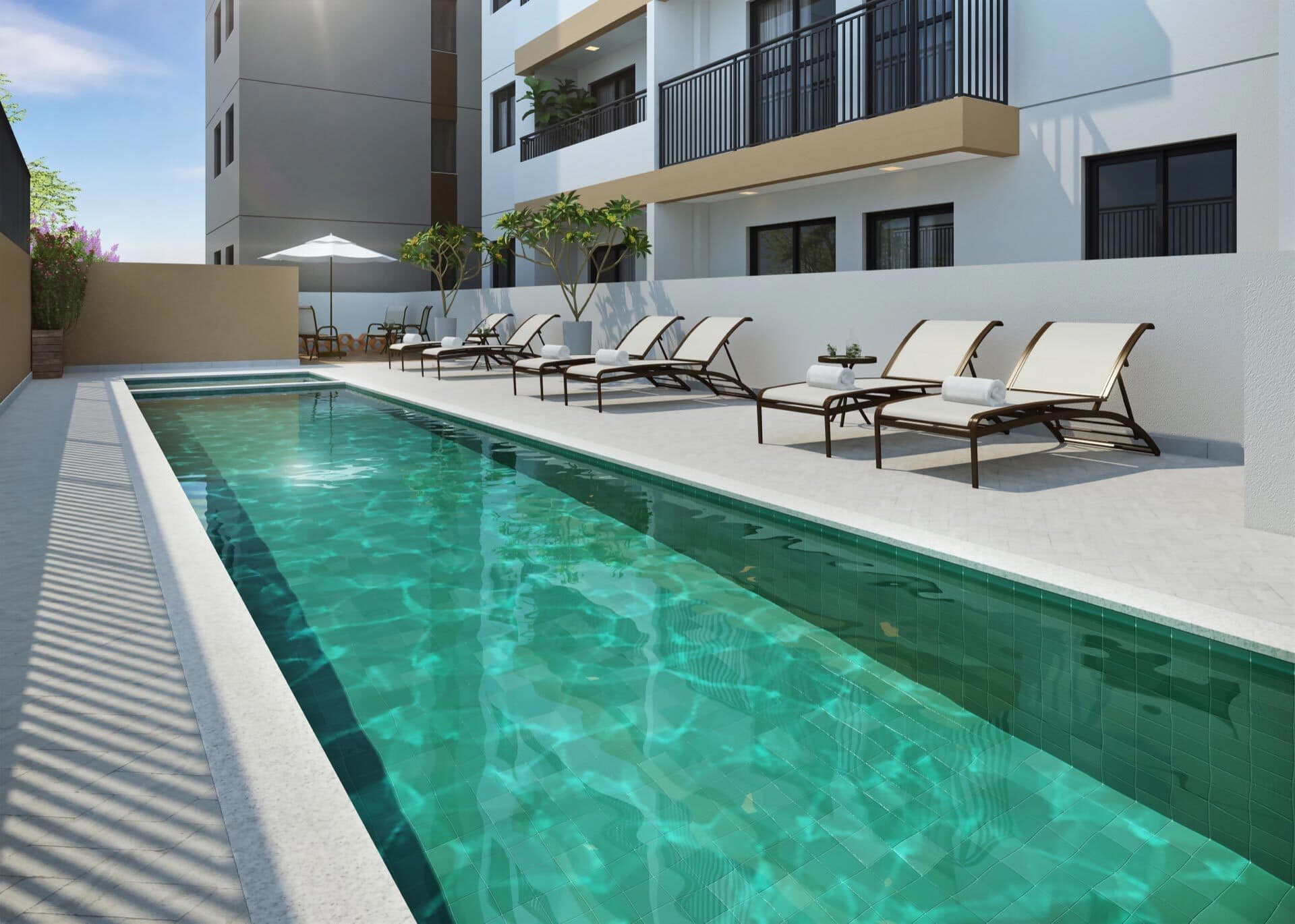 Piscina com raia cercada por espreguiçadeiras e deck externo.