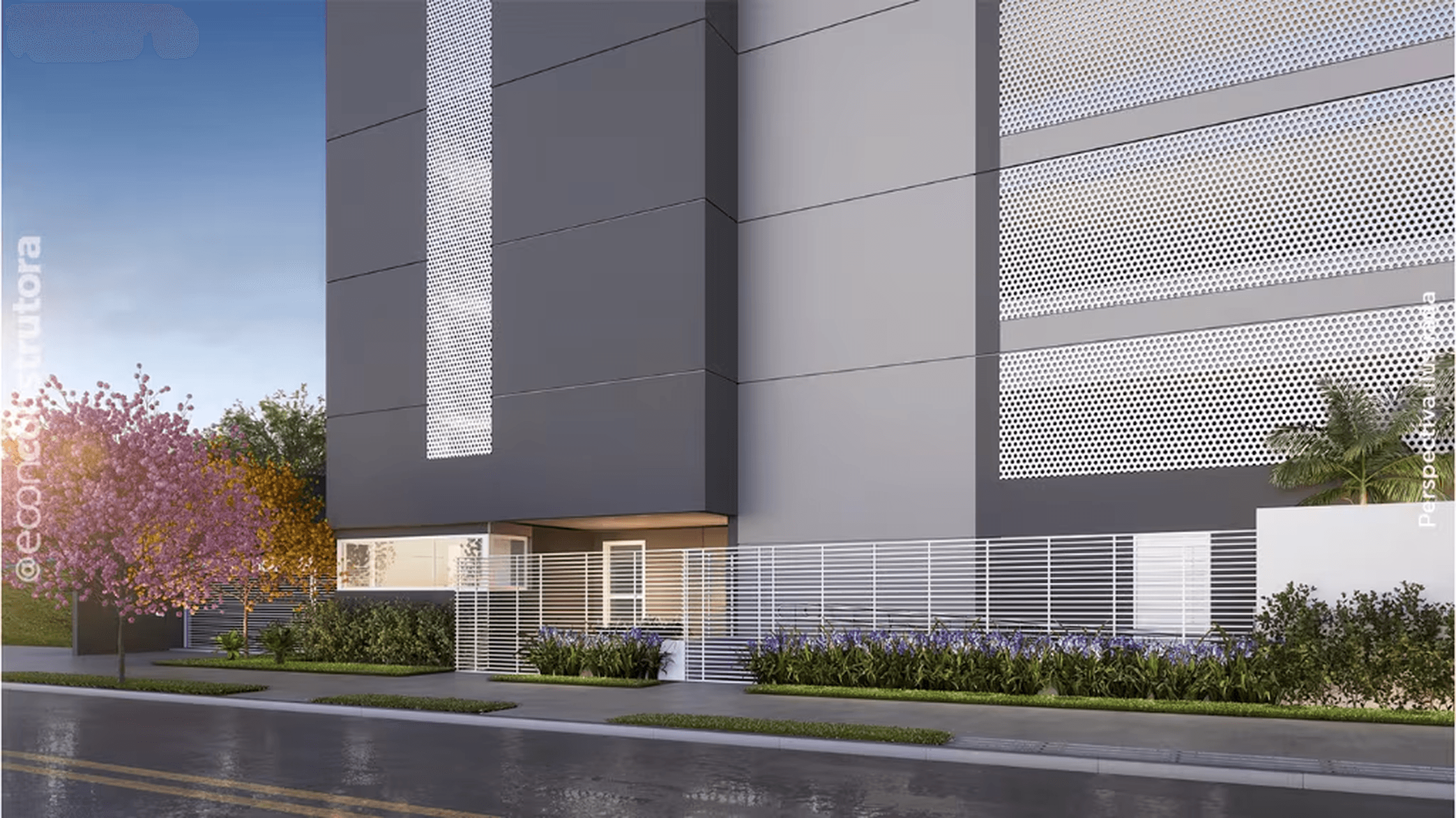 Fachada frontal do edifício com portão branco, grades e vegetação na calçada